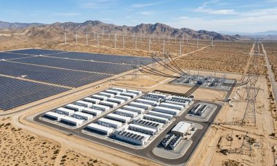 An aerial view of a utility-scale renewable energy complex supplying electricity to both a large Bitcoin mining facility and the regional power grid through high-voltage transmission infrastructure, illustrating how flexible mining supports renewable energy integration and grid reliability.