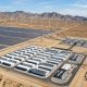An aerial view of a utility-scale renewable energy complex supplying electricity to both a large Bitcoin mining facility and the regional power grid through high-voltage transmission infrastructure, illustrating how flexible mining supports renewable energy integration and grid reliability.