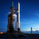 Blue Origin-style reusable heavy-lift rocket on a coastal launch pad at dawn